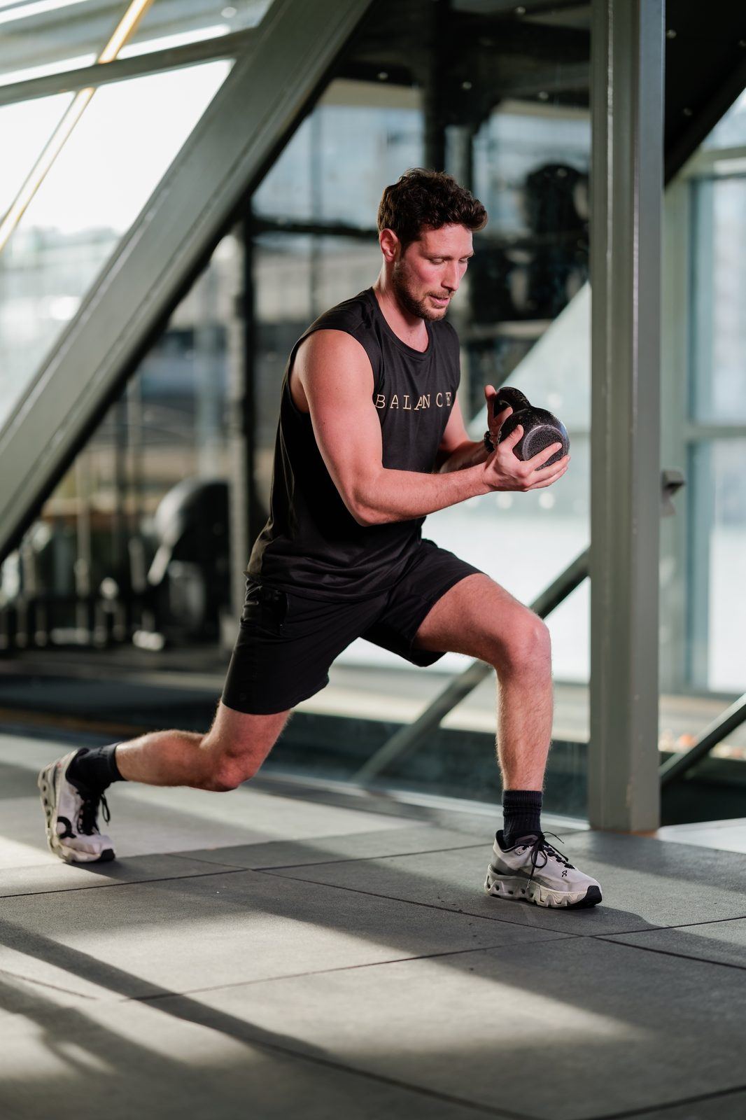 Homme actif réalisant un circuit court avec kettlebell dans une salle lumineuse, entraînement efficace et rapide